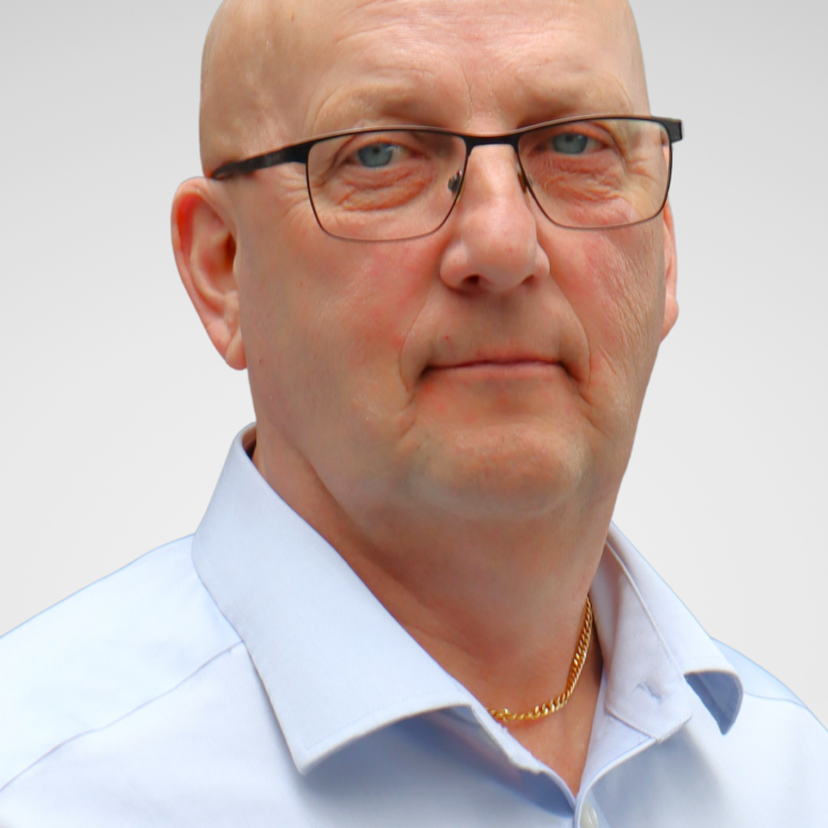 A man wearing glasses looking at the camera and smiling.