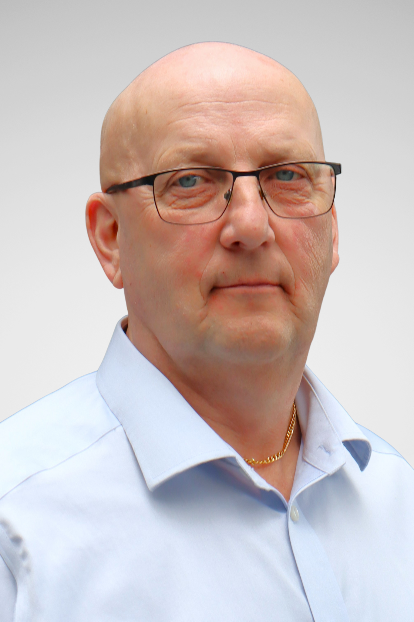 A man wearing glasses looking at the camera and smiling.