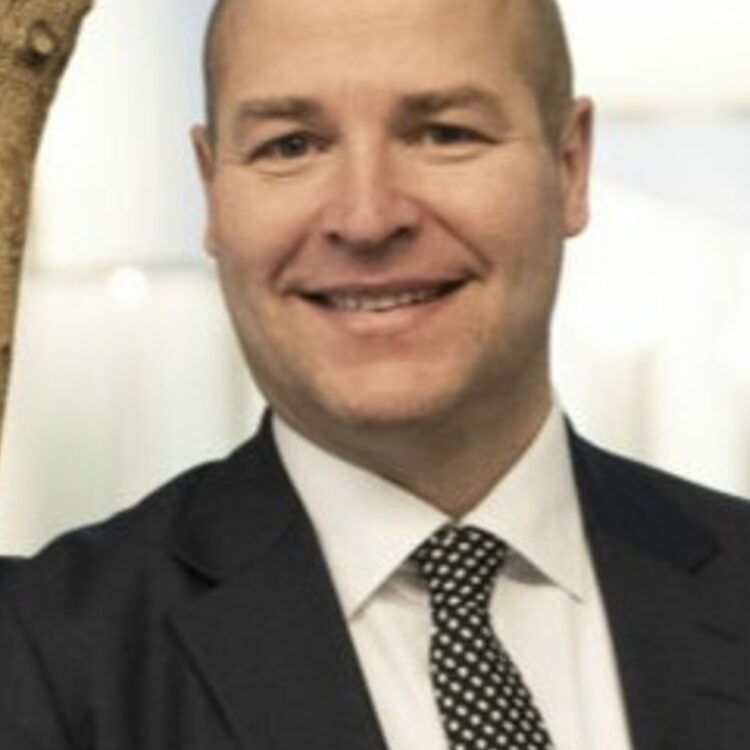 A man in suit looking at the camera and smiling.