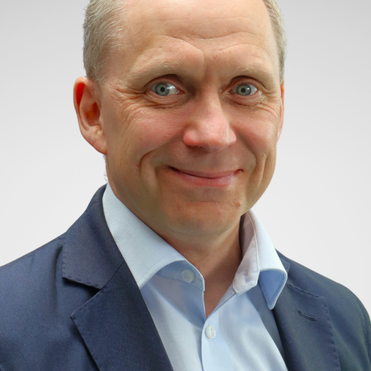 A man in suit looking at the camera and smiling.