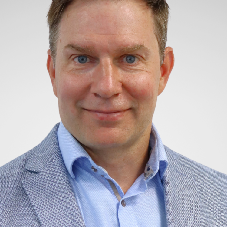 A man in suit looking at the camera and smiling.