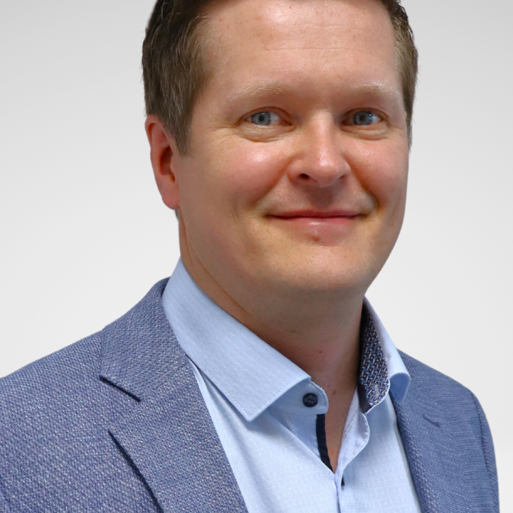 A man in suit looking at the camera and smiling.