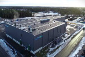 A production facility roof featuring numerous solar panels with a visible logo that says "Aurajoki".